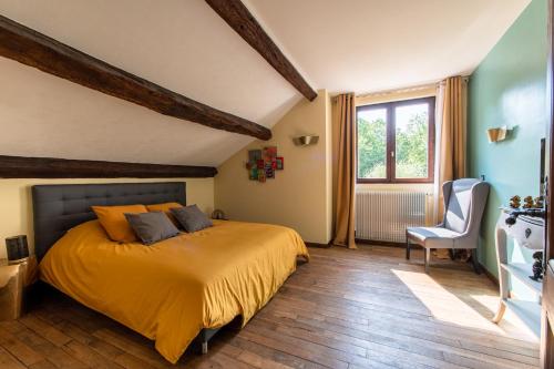 a bedroom with a bed and a chair and a window at L’étang des 7 in Thenay