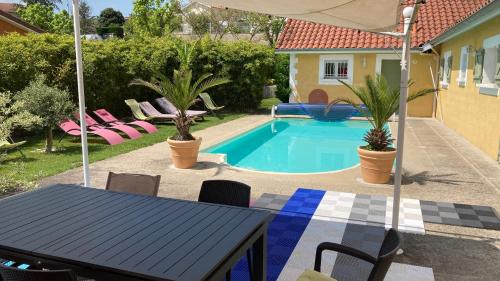 La Villa Coisy في سان غالمير: حديقة خلفية بها مسبح وطاولة وكراسي