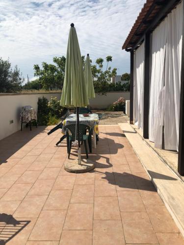 a patio with an umbrella and a table and chairs at Sirenetta in Torre Suda