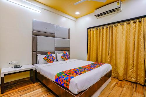 a bedroom with a bed and a yellow curtain at FabHotel Tanishq in Sinnar