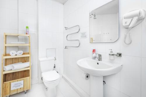 a white bathroom with a toilet and a sink at Arzni Health Resort in Arzni