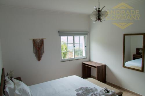 een witte slaapkamer met een bed en een spiegel bij Casa da Calçada Guest House in Pinhão