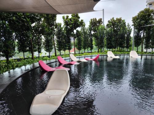 une rangée de chaises roses et blanches dans une piscine d'eau dans l'établissement opus residences by sunflower, à Kuala Lumpur