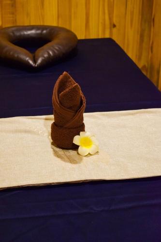 a piece of brown towel with a flower on a bed at Pride Hotel And Resort Rishikesh in Rishīkesh