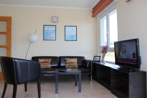 uma sala de estar com um sofá preto e uma televisão em Vistas al mar em Porto de Espasante