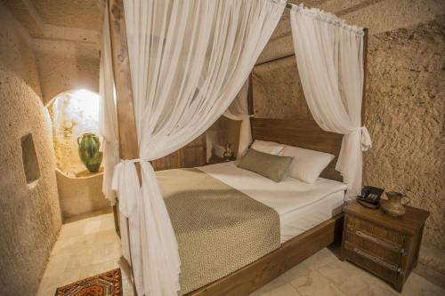 ウチヒサールにあるHelike in Cappadociaのベッドルーム(白いカーテン付きの天蓋付きベッド1台付)