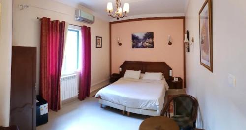 um quarto com uma cama e uma janela em Hotel Les Ambassadeurs em Orã