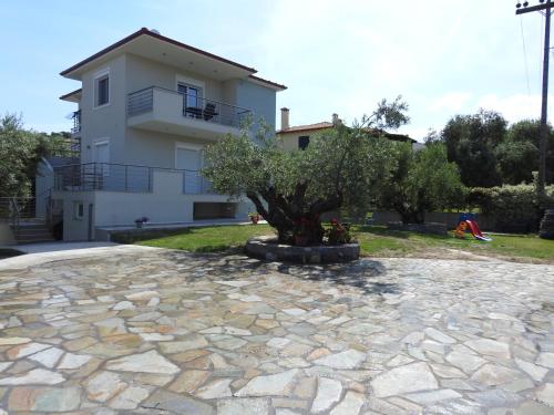 a house with a tree on a stone driveway at Sandra's luxury stay in Akti Salonikiou