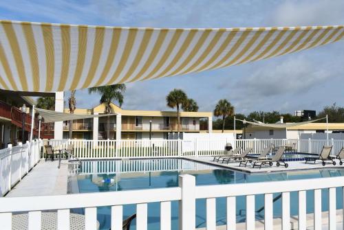 a swimming pool with chairs and a white fence at Super 8 by Wyndham Ocala I-75 in Ocala