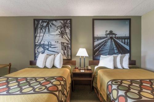 ein Hotelzimmer mit 2 Betten und einem Gemälde an der Wand in der Unterkunft Super 8 by Wyndham Ocala I-75 in Ocala