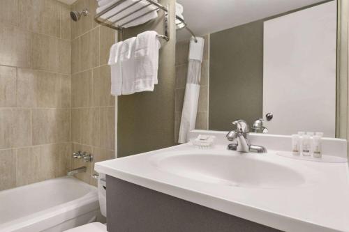 a bathroom with a sink and a tub and a mirror at Days Inn by Wyndham Fallsview in Niagara Falls