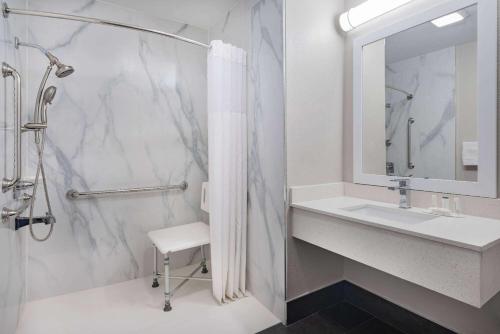 a bathroom with a shower and a sink and a mirror at Days Inn by Wyndham Hamilton in Hamilton