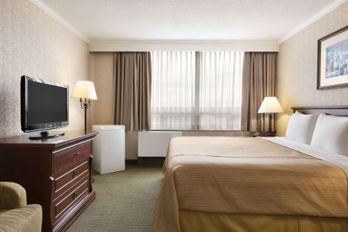 a hotel room with a bed and a flat screen tv at Days Inn by Wyndham Ottawa West in Ottawa