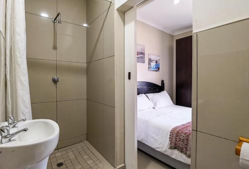 y baño con lavabo, cama y ducha. en Ballito Backpackers, en Ballito