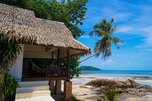 a hut on a beach with a palm tree and the ocean at Ocean Vibes in Thong Sala