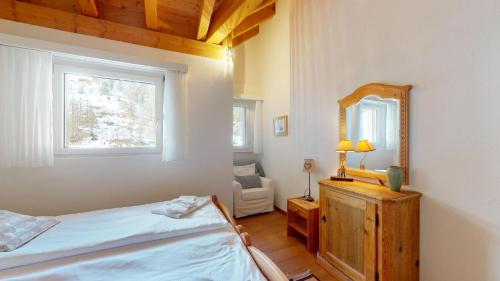 um quarto com uma cama, um espelho e uma cadeira em Abitaziun Ruinatsch 45 - St Moritz em St. Moritz