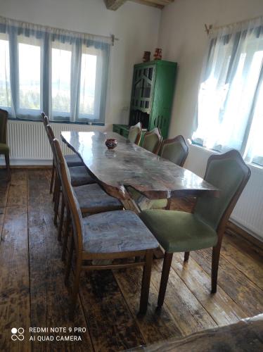 a dining room with a wooden table and chairs at Căsuța de la munte in Bistriţa