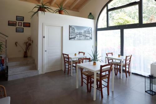 ein Esszimmer mit Tischen, Stühlen und Fenstern in der Unterkunft Ca' del Portego in Tessera