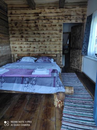 a bedroom with a bed and a wooden wall at Căsuța de la munte in Bistriţa