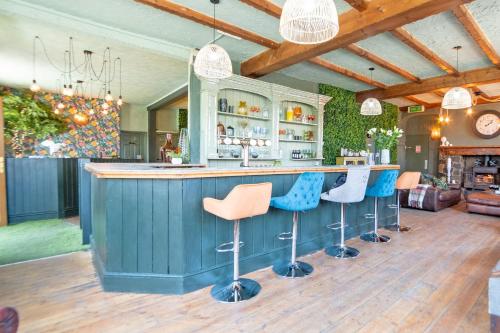 a kitchen with a bar with blue and orange stools at Waterfall Country Escape Entire Venue Sleeps 19 - Brecon Beacons National Park Wales in Coelbren
