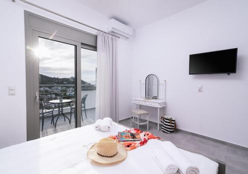 a bedroom with a bed and a television and a balcony at Lychnos apartments in Kamilari