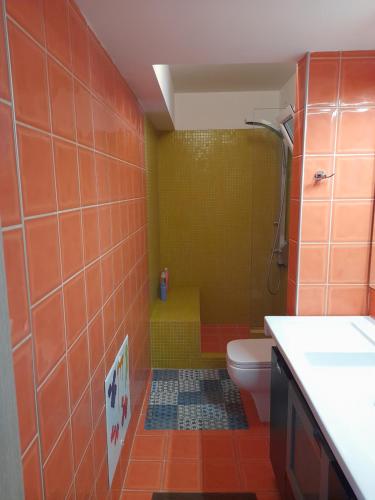 a bathroom with a shower and a toilet with orange tiles at Bright top floor apartment! in Zakynthos