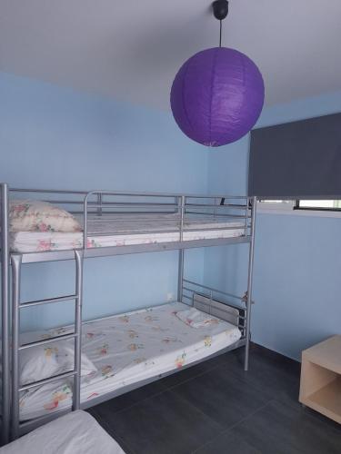 a room with three bunk beds with a purple lamp at Bright top floor apartment! in Zakynthos Town