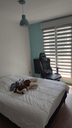 un lit avec un animal en peluche dessus avec une chaise dans l'établissement Magnifique maison à 5 mns du circuit des 24h à pieds, au Mans
