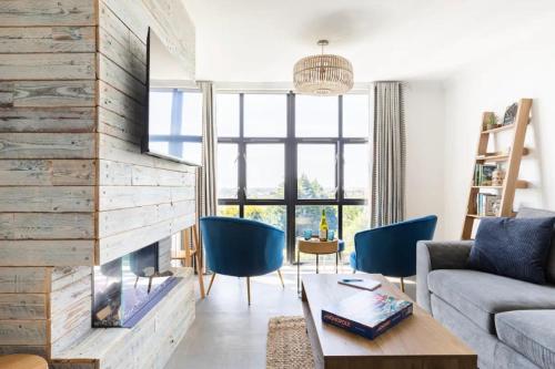 a living room with a fireplace and blue chairs at 5 mins from the Eden Project Baybreeze Holiday Apartment, Sea Views, Super Kingsize Beds in St Austell