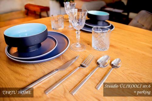 a table with plates and silverware on a wooden table at University City Heart, Tartu Home in Tartu