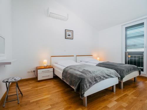 a white bedroom with two beds and a window at Apartment Jagoda Okrug Gornji in Trogir