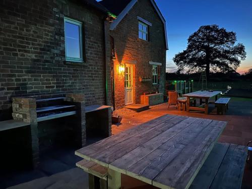 un patio con una mesa de madera y un edificio de ladrillo en The Coach House 1861 en Penrith