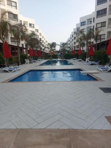 einen Pool in einem Resort mit Stühlen und Sonnenschirmen in der Unterkunft بورتو سعيد - Porto Said in `Ezbet Shalabi el-Rûdi