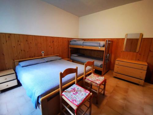 a bedroom with a bed and two chairs in it at APPARTAMENTO S.ANNA IN VALMALENCO in Torre di Santa Maria