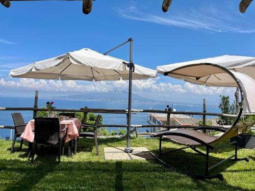 einen Tisch und Stühle unter einem Regenschirm neben dem Wasser in der Unterkunft La Badia Montechiaro - Breathtaking View of Sorrento Coast in Vico Equense