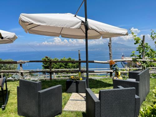 ein weißer Regenschirm und Stühle mit dem Ozean im Hintergrund in der Unterkunft La Badia Montechiaro - Breathtaking View of Sorrento Coast in Vico Equense