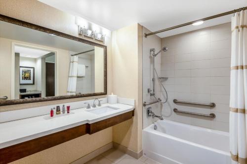 y baño con lavabo, bañera y espejo. en Denver Marriott Westminster, en Westminster