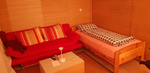 een kleine kamer met een rode bank en een tafel bij Souterrain Zimmer mit Sauna in Klosterlechfeld