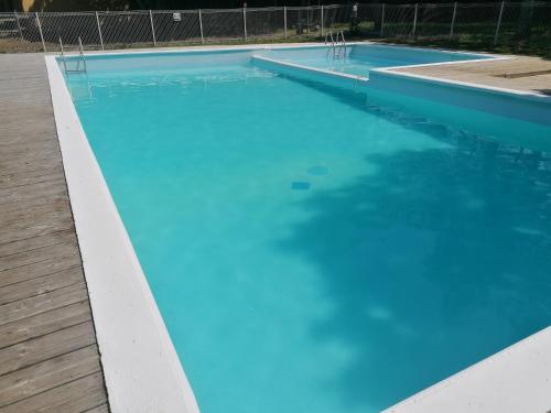 uma grande piscina azul com um deque de madeira em L escale de larcher em Saint-Aubin-de-Nabirat