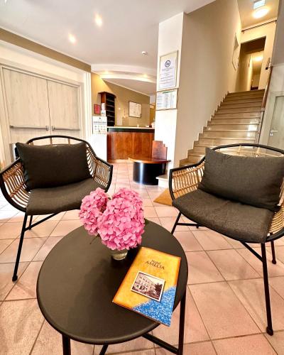 a living room with two chairs and a table with flowers at Hotel Amelia in Fano