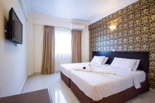 a bedroom with a large bed with a tv on a wall at Hotel Sea Princess in Teluk Bahang