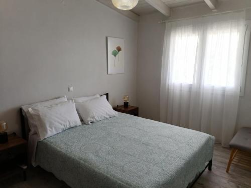 a white bedroom with a bed and a window at Panoramic view in Preveza