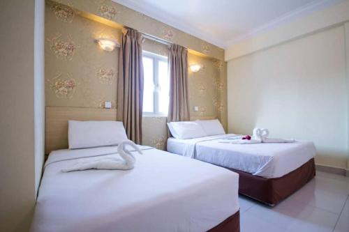 a hotel room with two beds and a window at Hotel Sea Princess in Teluk Bahang
