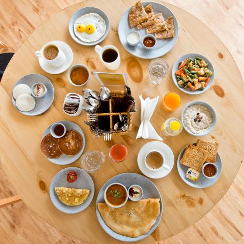a table with plates of breakfast food on it at Bloom Hotel - HSR Club in Bengaluru