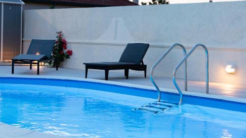 Booking Zaton Villa Martinova holiday house with swimming pool في زاتون: مسبح مع كرسيين وكرسي في الماء