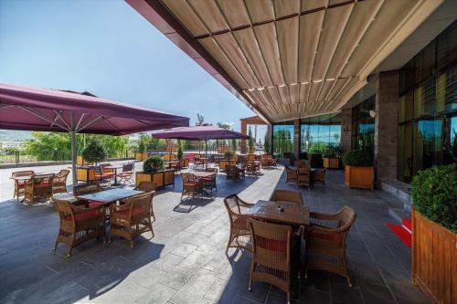an outdoor patio with tables and chairs and umbrellas at Ramada By Wyndham Cappadocia in Ortahisar