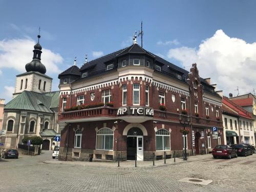 a large red brick building with a clock tower at Pokoje W Pięknej Kamienicy W Centrum W Głogówku in Głogówek