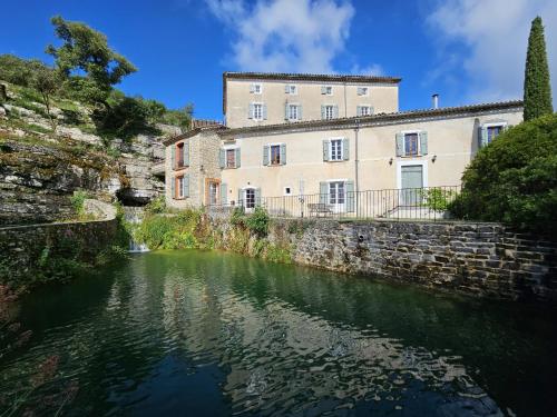 a building next to a river in front of a building at Domaine de Bagard - Village de gîtes - nature et authenticité in Sauve