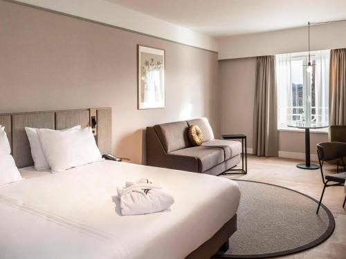 um quarto de hotel com uma cama e uma cadeira em Mercure Liege City Centre em Liège