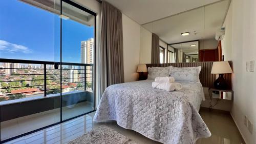 a bedroom with a bed and a large window at Apartamento ao lado Flamboyant Shopping em Goiânia in Goiânia
